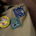 Patches on a beige bag including a blue patch with 'Gualms' text and star design.