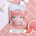 Package of naturebee shower steamers with grapefruit slices on a pink tiled background