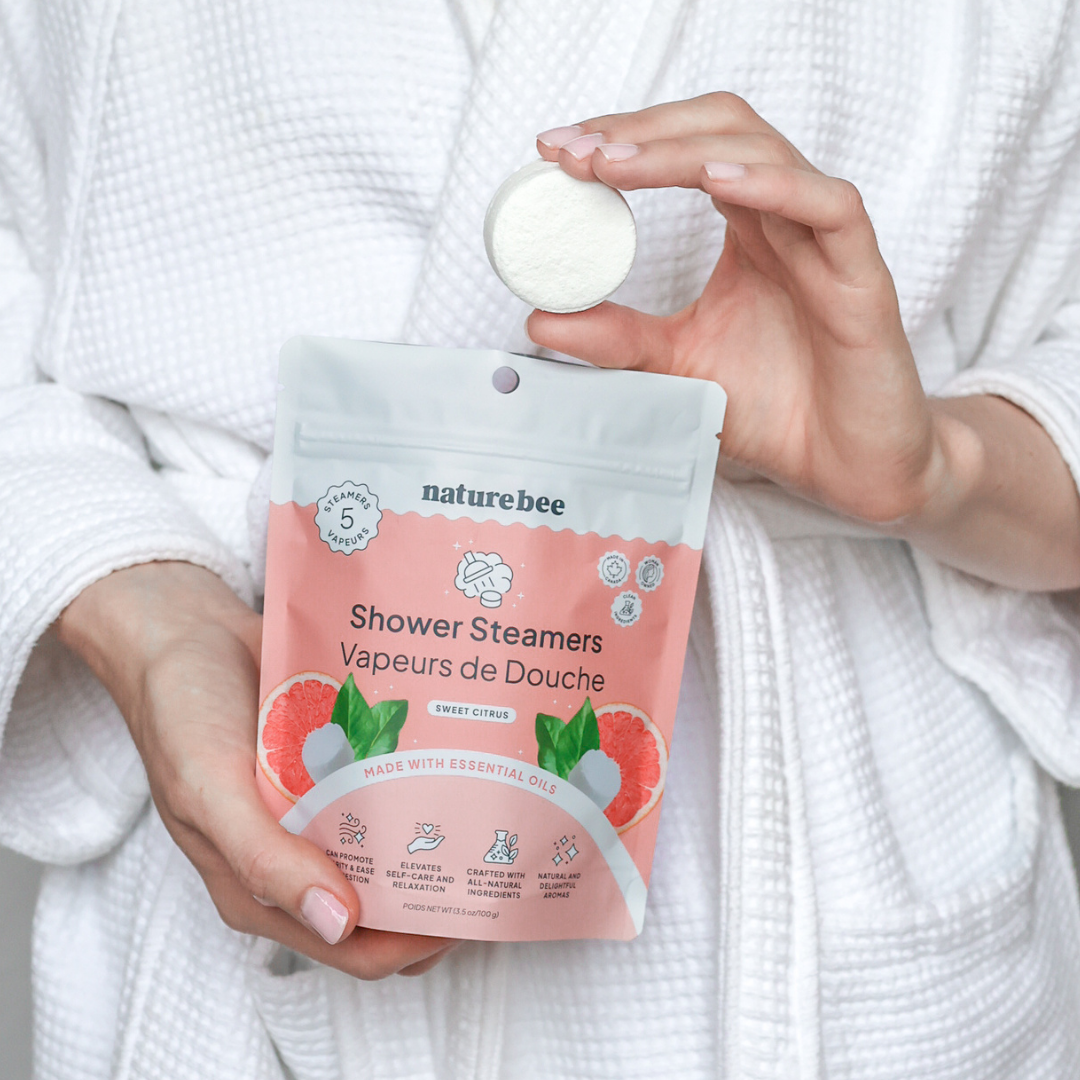 Person holding a package of NatureBee shower steamers with a white robe.