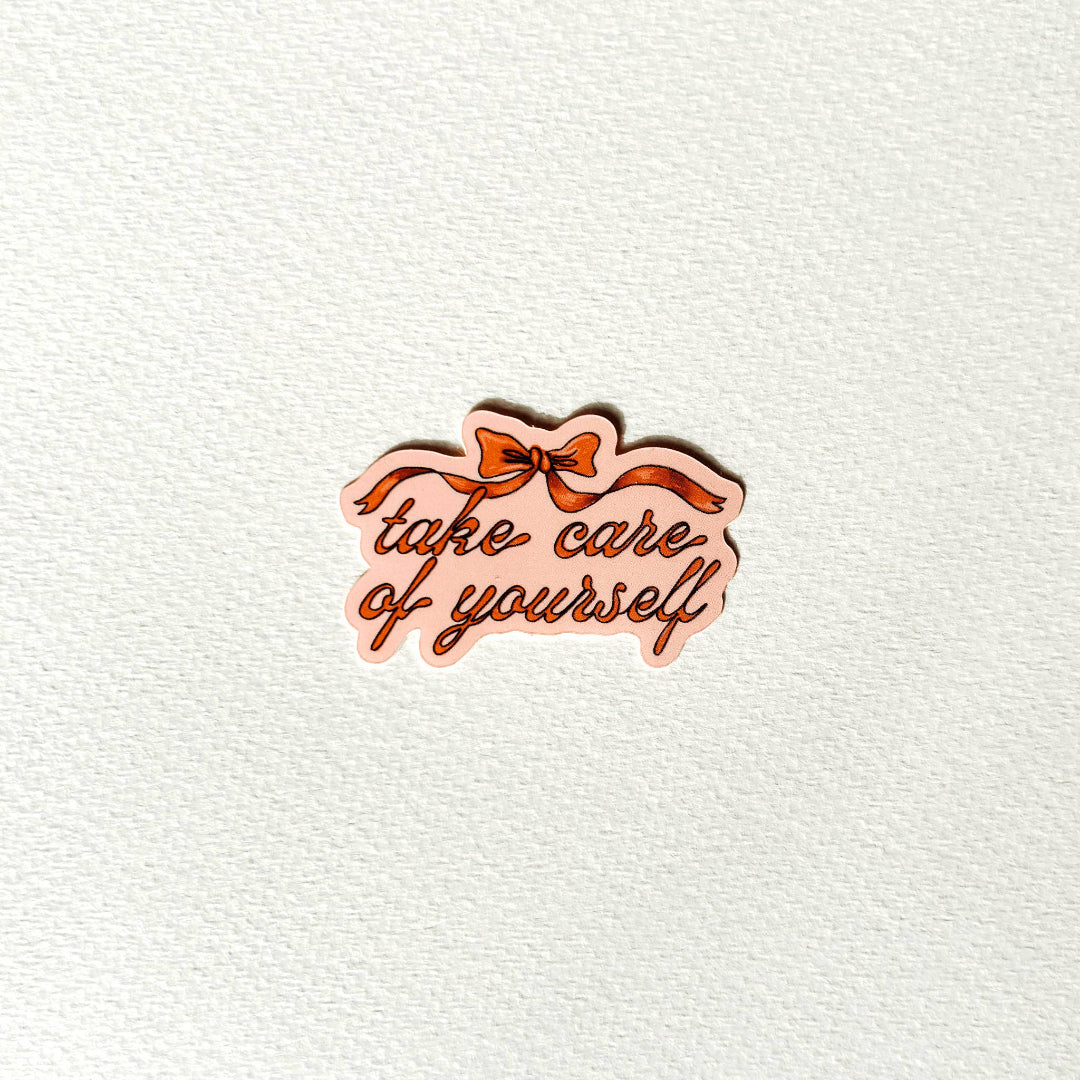 Decorative pin with 'take care of yourself' text and a bow on a textured white background