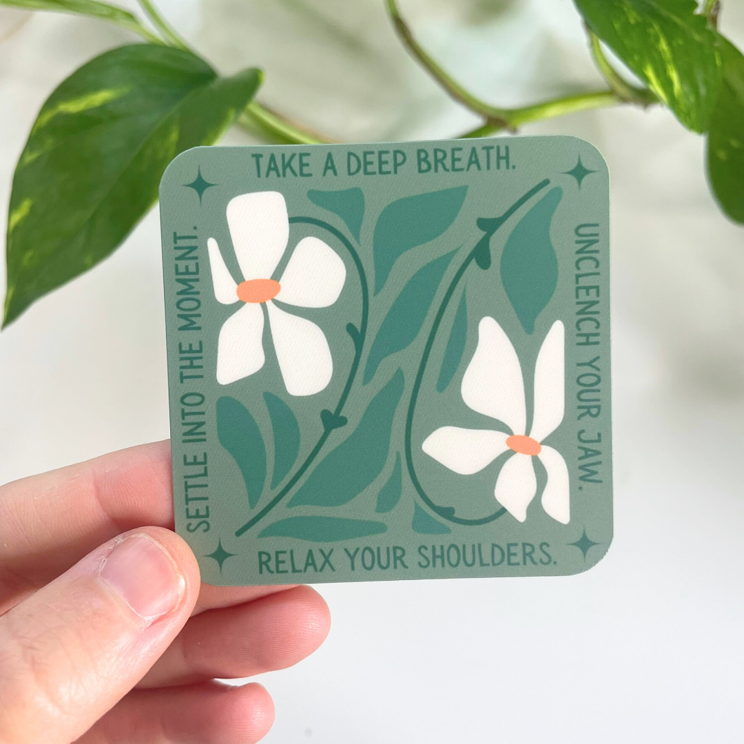 Card with floral design and relaxation instructions held by a hand with a plant in the background