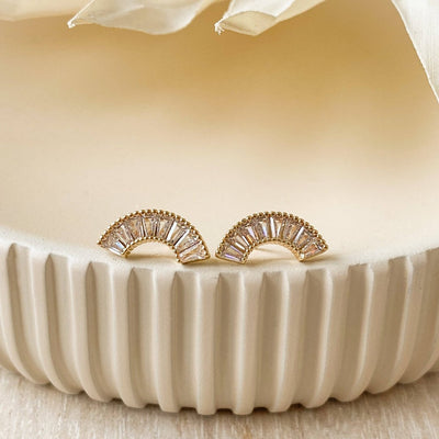 A pair of gold-plated stud earrings with a semicircle design. The earrings are adorned with multiple small cubic zirconia stones arranged in a fan shape.