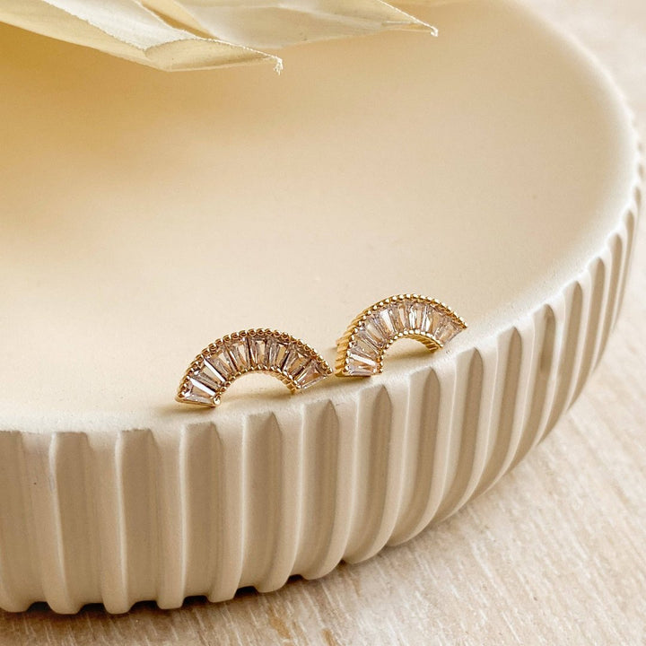 A pair of gold-plated stud earrings with a semicircle design. The earrings are adorned with multiple small cubic zirconia stones arranged in a fan shape.