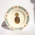 Decorative plate with gold pineapple design on a white background