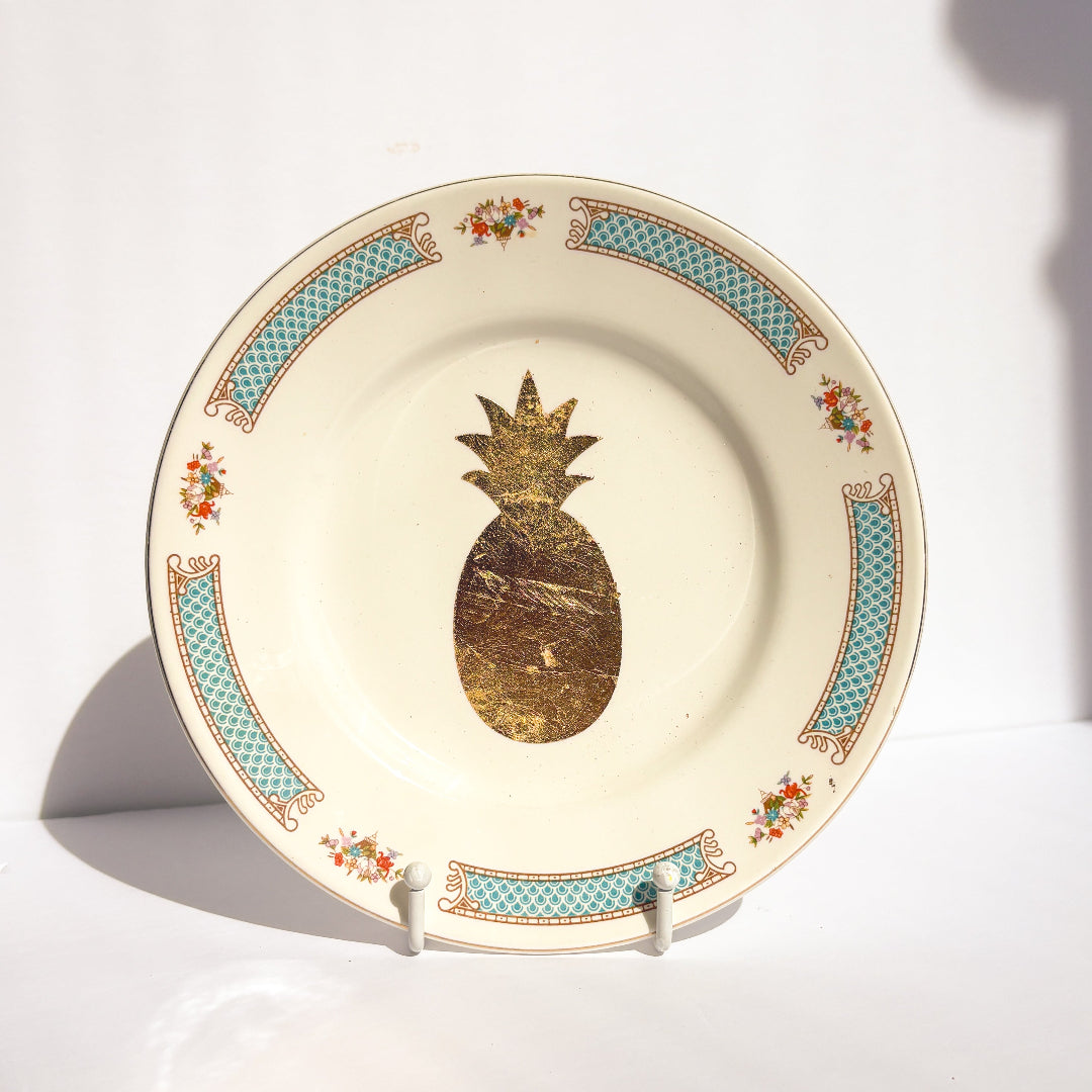 Decorative plate with gold pineapple design on a white background