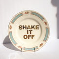 Decorative plate with 'SHAKE IT OFF' text on a white background