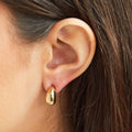 Gold earring worn by a person with brown hair