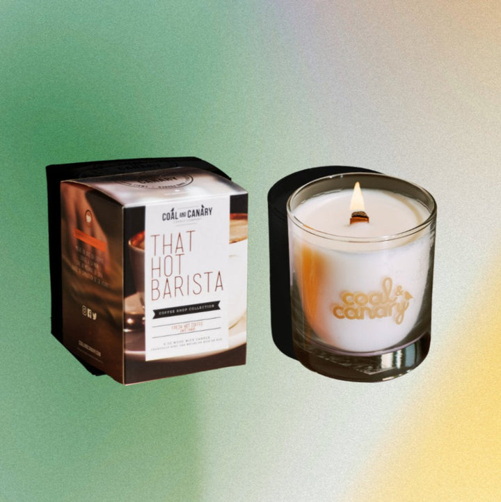 A white candle with a gold logo that says 