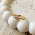 A gold ring with a cluster of small, clear stones set in a curved band.