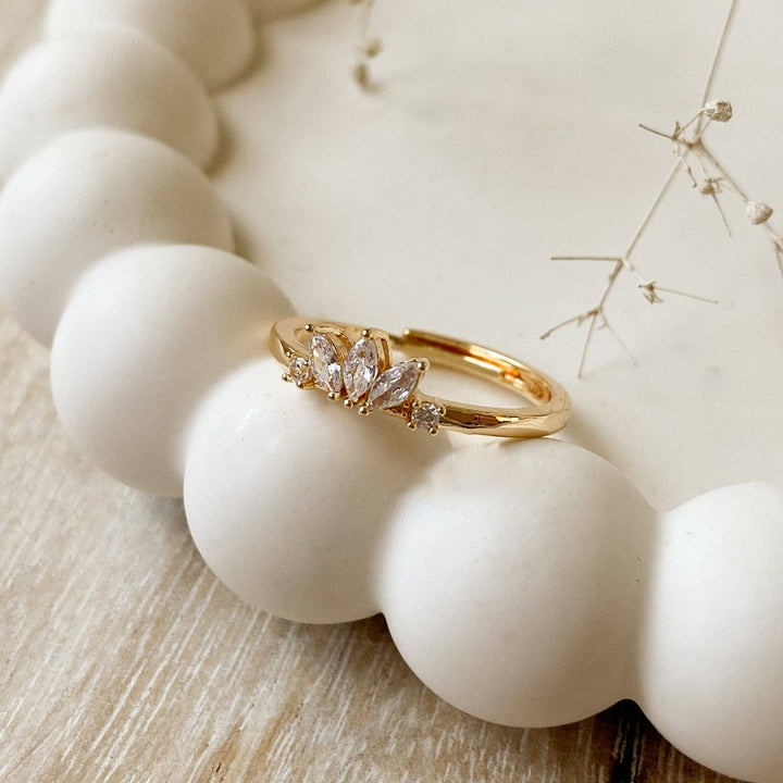 A gold ring with a cluster of small, clear stones set in a curved band.