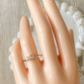 A gold ring with a cluster of small, clear stones set in a curved band.