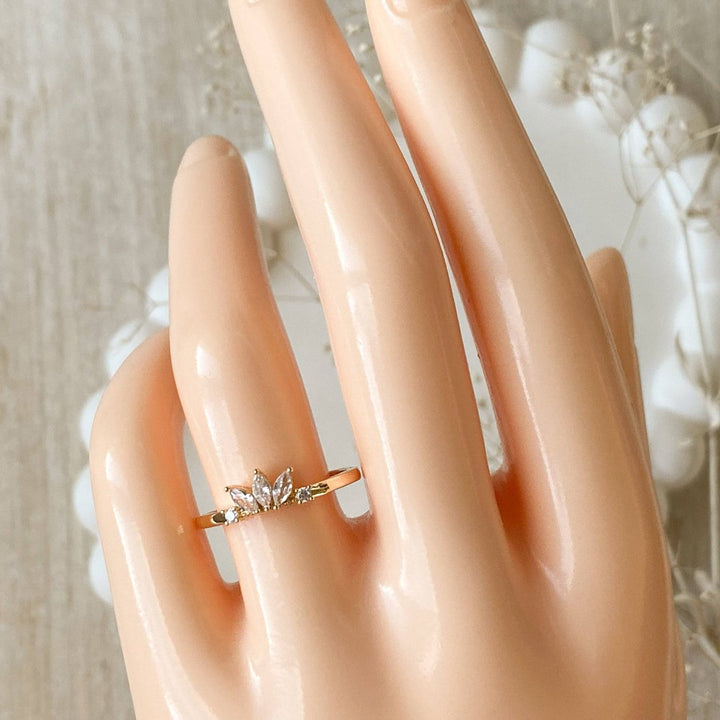 A gold ring with a cluster of small, clear stones set in a curved band.