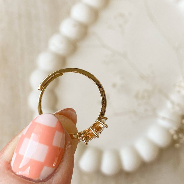 A gold ring with a cluster of small, clear stones set in a curved band.