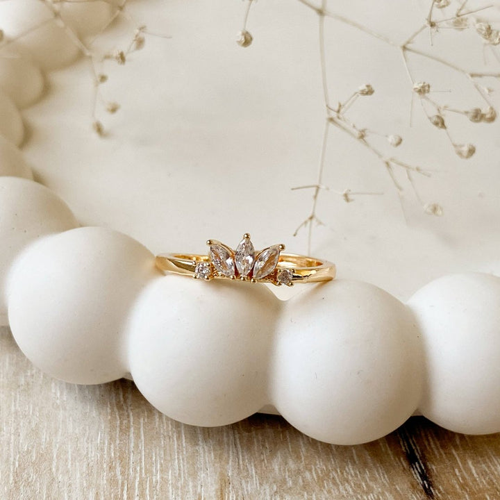 A gold ring with a cluster of small, clear stones set in a curved band.