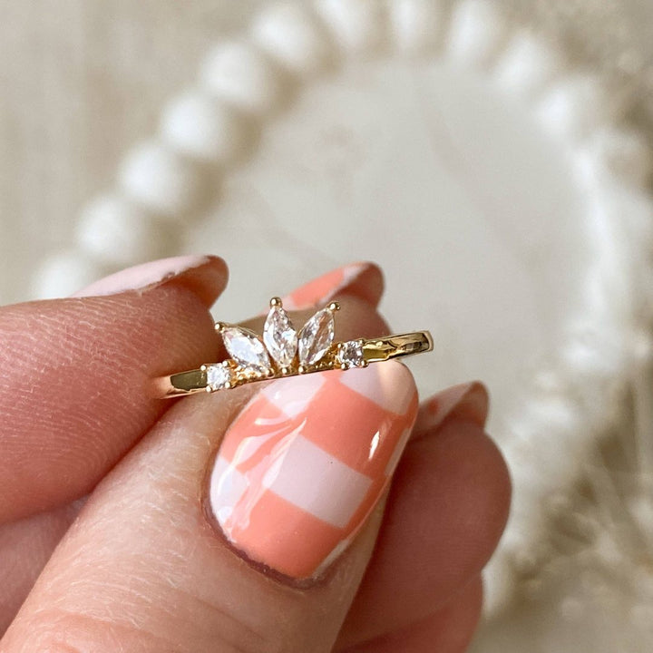 A gold ring with a cluster of small, clear stones set in a curved band.