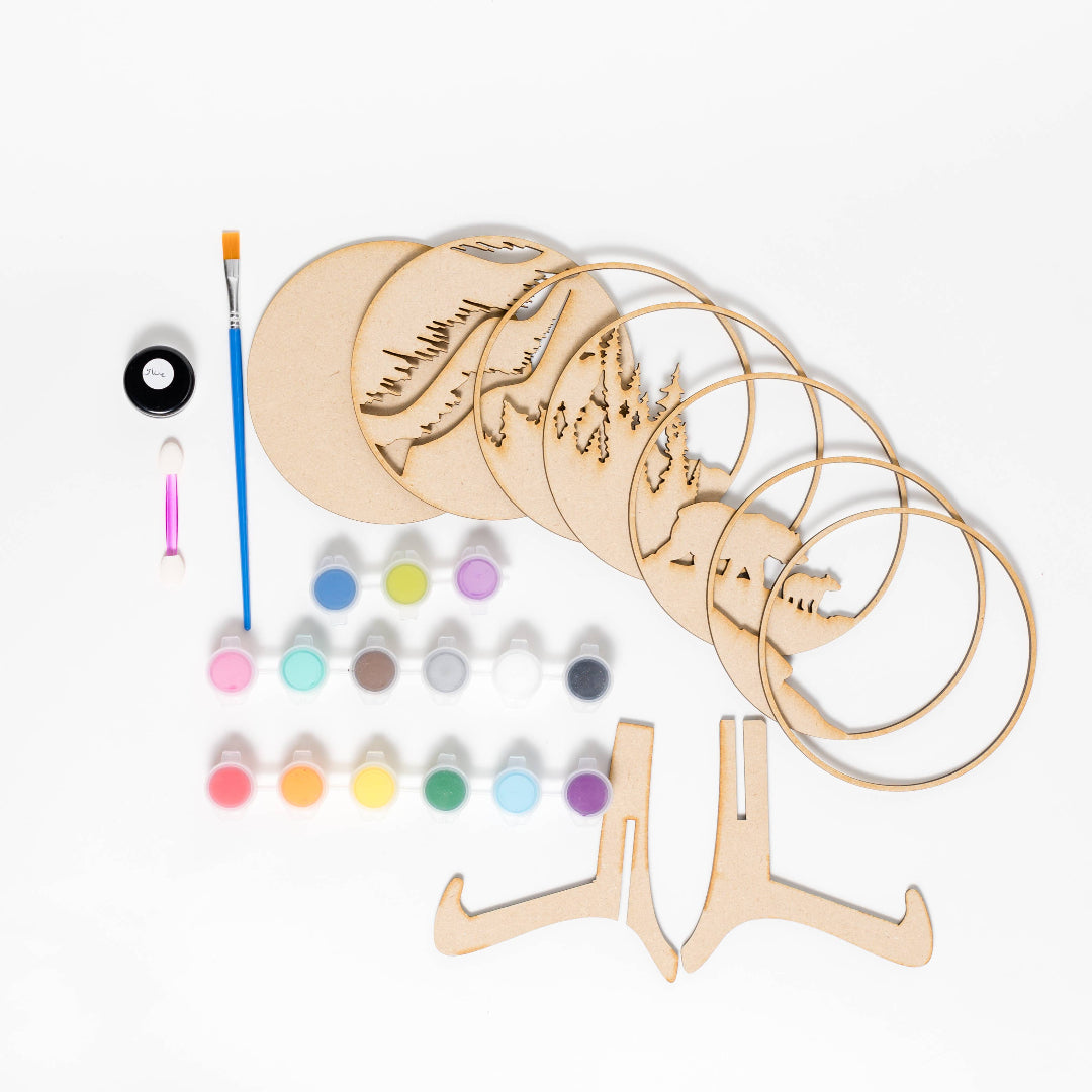 Wooden coasters with decorative designs, paint bottles, and a brush on a white background