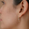 A pair of minimalist U-shaped stud earrings crafted from delicate 14 KT gold wire. Each earring features a short segment of tiny Japanese glass seed beads in a subtle and elegant pattern of cream, pale pink, soft teal, warm beige, and a touch of gold near the top of the hanging bar.