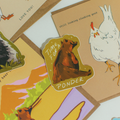 A die-cut sticker featuring a brown bear sitting thoughtfully with the text 'TIME FOR PONDER' on a tan background, displayed on top of illustrated cards.