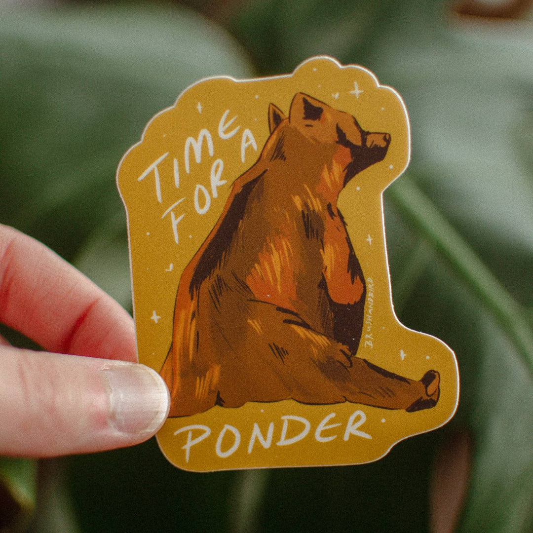 Sticker with a bear illustration and text 'Time for a Ponder' held by a hand against a leafy background.