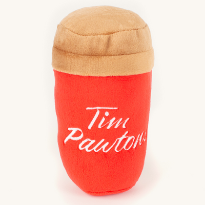 A red, plush dog toy shaped like a coffee can. The toy has a brown lid and a label that says 
