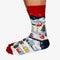 A pair of colorful socks with a winter scene. The socks feature houses, trees, and snowmen on a snowy landscape.