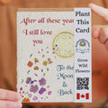 Seeded card with floral design and text, held by a person against a blurred background