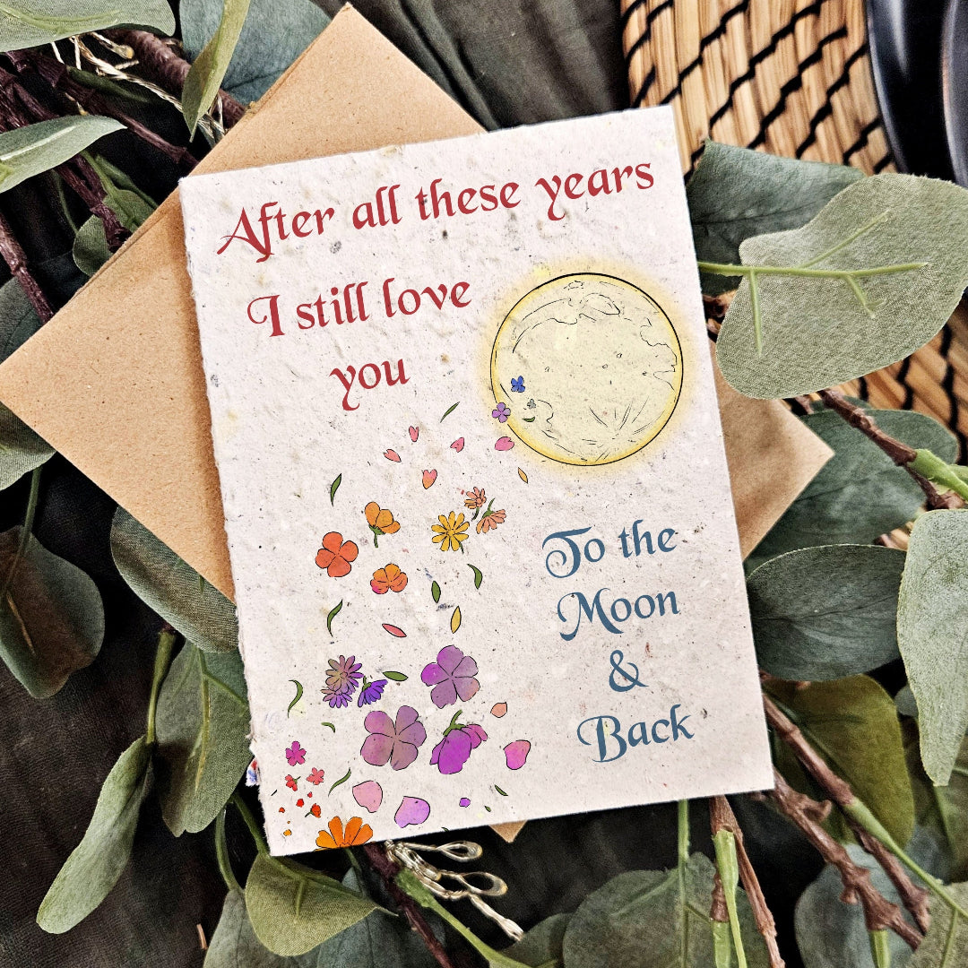 Greeting card with floral design and text 'After all these years I still love you To the Moon & Back' on a leafy background.