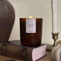 Candle labeled 'toasted vanilla' on a book with a blurred background