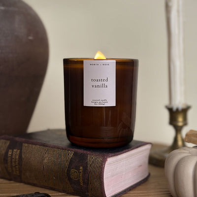 Candle labeled 'toasted vanilla' on a book with a blurred background