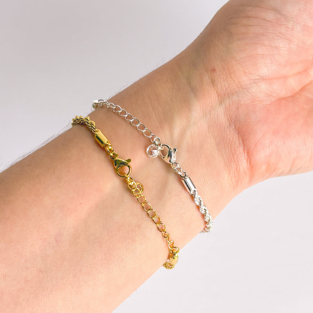 Two gold and silver bracelets on a wrist against a white background