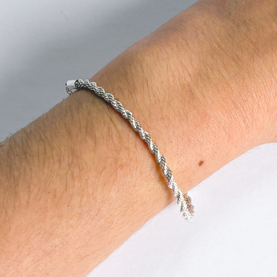 Silver braided bracelet on a wrist with a neutral background