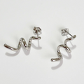 A pair of twisty coil earrings made of sterling silver, featuring a unique, abstract, and wavy design, displayed on a light-colored surface. These modern earrings are available in Ottawa, Ontario, Canada.