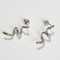 A pair of twisty coil earrings made of sterling silver, featuring a unique, abstract, and wavy design, displayed on a light-colored surface. These modern earrings are available in Ottawa, Ontario, Canada.