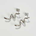 A pair of twisty coil earrings made of sterling silver, featuring a unique, abstract, and wavy design, displayed on a light-colored surface. These modern earrings are available in Ottawa, Ontario, Canada.