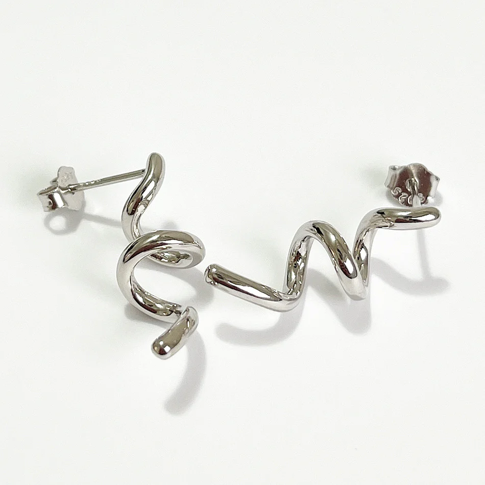 A pair of twisty coil earrings made of sterling silver, featuring a unique, abstract, and wavy design, displayed on a light-colored surface. These modern earrings are available in Ottawa, Ontario, Canada.