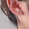 A pair of twisty knot stud earrings made of sterling silver, featuring a unique, abstract, and intertwined design, displayed on a book with dried flowers and a glass object. These modern earrings are available in Ottawa, Ontario, Canada.