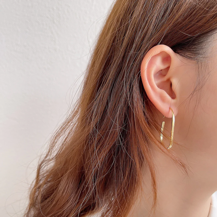 U-shaped open hoop earrings made with 18k gold plating, featuring a modern, minimalist, and open curved design, displayed on a white background. These unique earrings are available in Ottawa, Ontario, Canada.