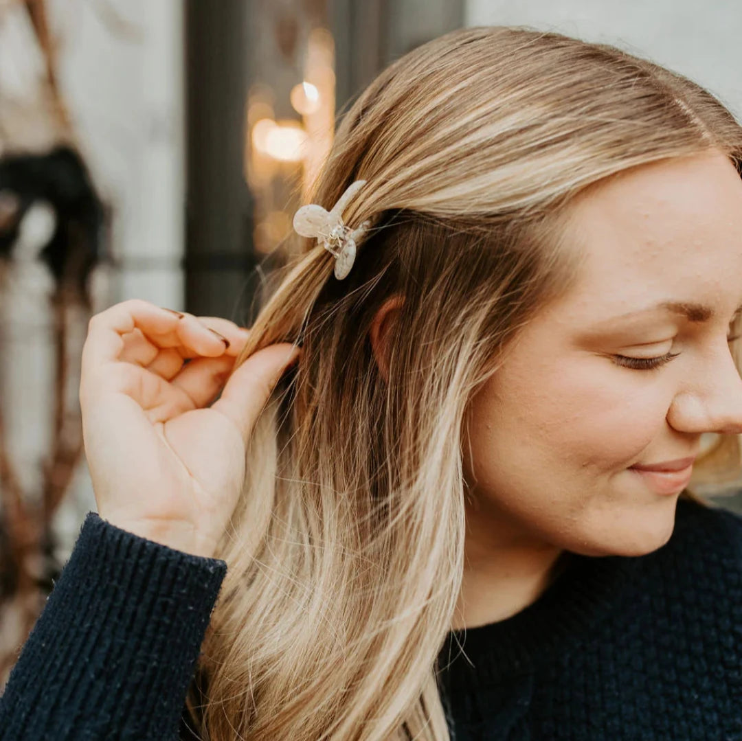 A small cream hair claw clip modeled in a persons hair.