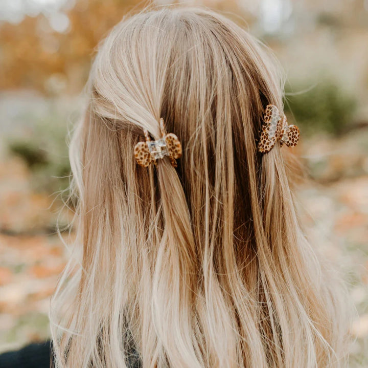 Two small cream hair claw clips modeled in a persons hair.