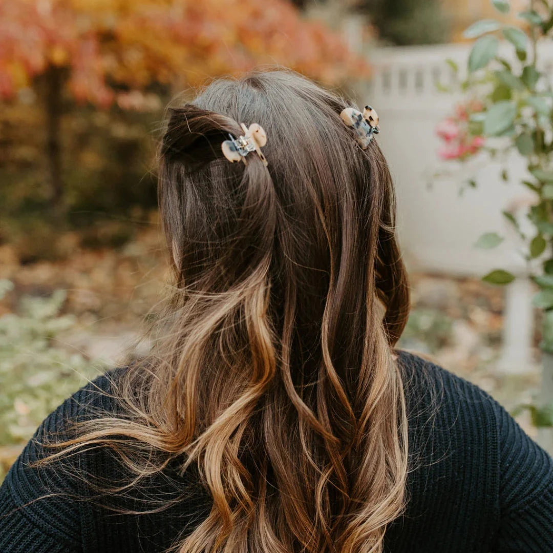A small cream hair claw clip modeled in a persons hair.