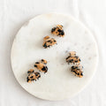 Six small, light tortoise hair claw clips arranged on a white marble surface. The clips have a marbled texture.
