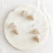Six small, creamy hair claw clips arranged on a white marble surface. The clips have a marbled texture.