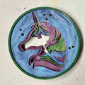 Decorative circular piece with a unicorn design on a textured surface
