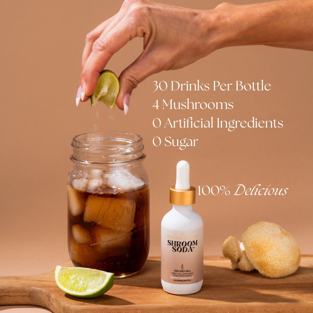 Shroom Soda bottle with a hand adding a lime wedge to a glass of iced drink on a wooden board.