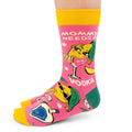 A pair of bright pink novelty crew socks with yellow toes and cuffs, featuring a cartoon vodka bottle and martini glass character with the text 'MOMMY NEEDS A VODKA' on a white background.