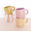 Set of four ceramic mugs with striped patterns on a light background
