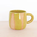 Green ceramic mug with pink interior on a beige background