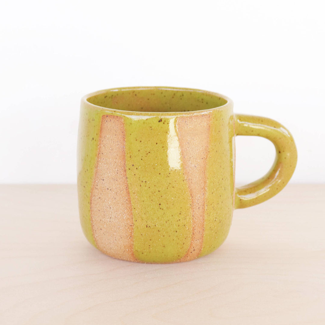 Green ceramic mug with pink interior on a beige background