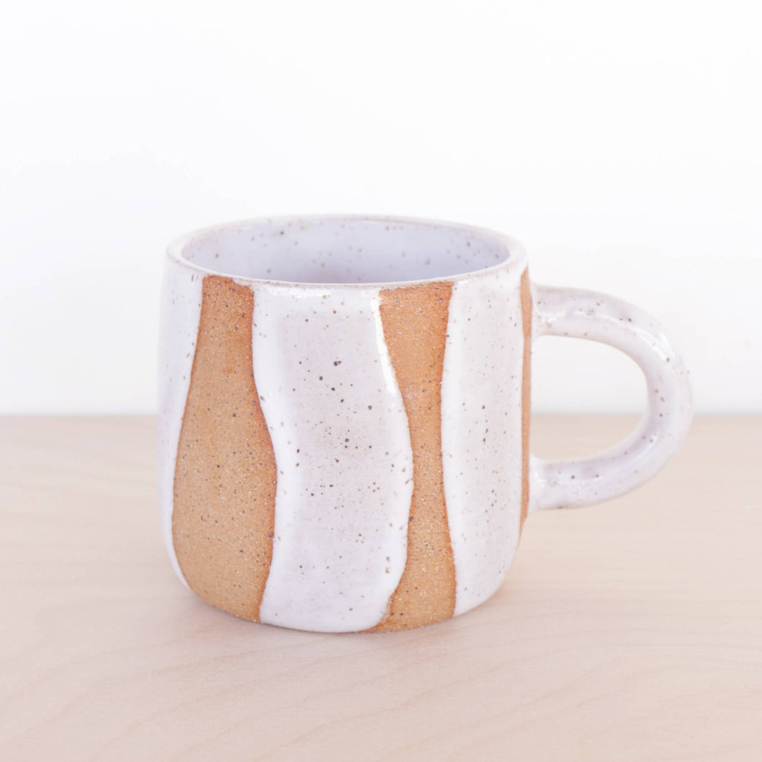 Ceramic mug with white and brown design on a beige background