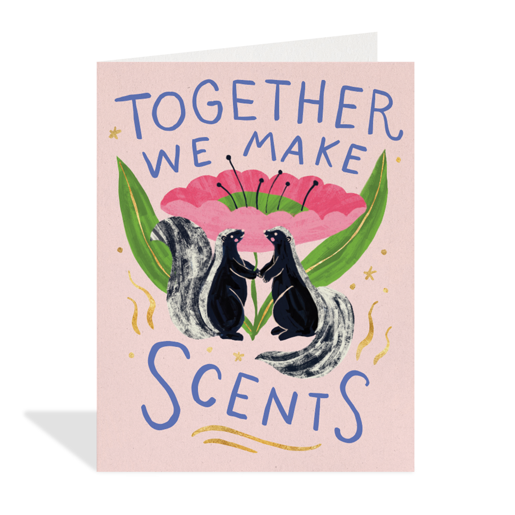 Greeting card with two skunks holding a flower and text 'Together we make scents' on a pink background.